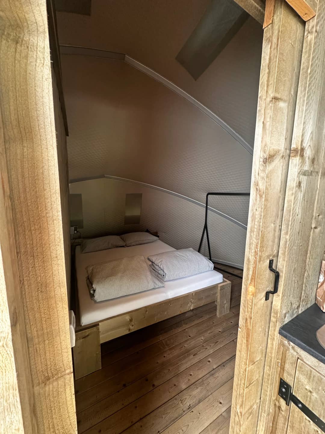 Bedroom at the Big Oak Lodge XL with a wooden double bed beneath the curved wall, as seen through the doorway