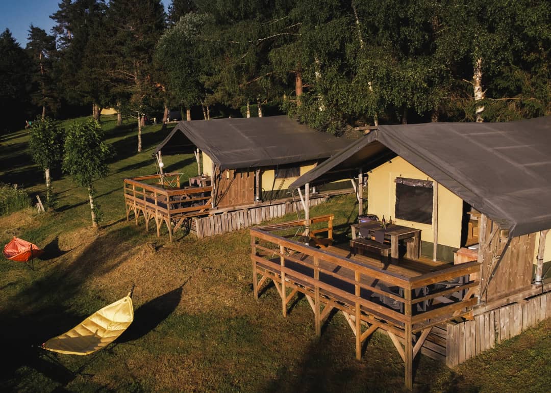 Two Base Lodges on stilts with a terrace bathed in the evening sun at Les Sapins