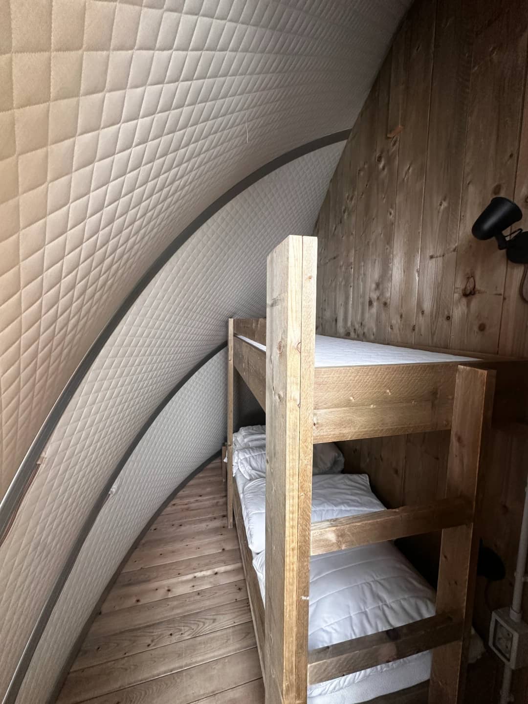 Wooden bunk bed with white bed linen beneath the padded, curved wall of the Big Oak Lodge XL